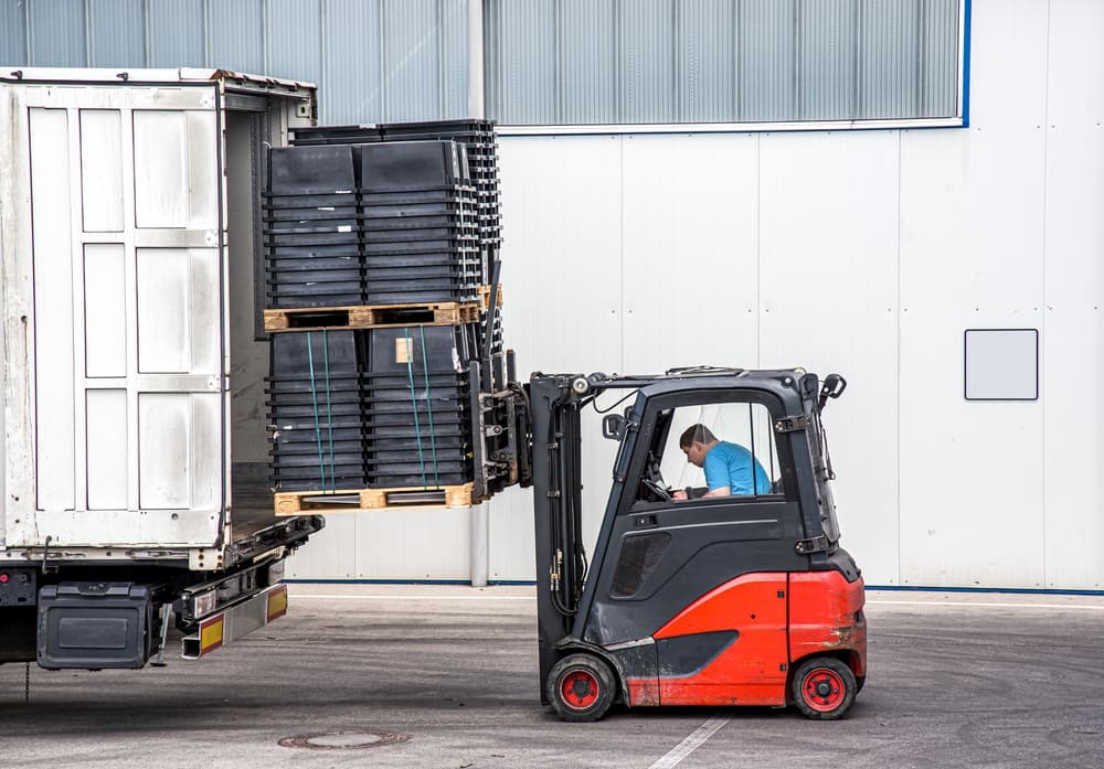 forklift loading pallets into a semi-truck