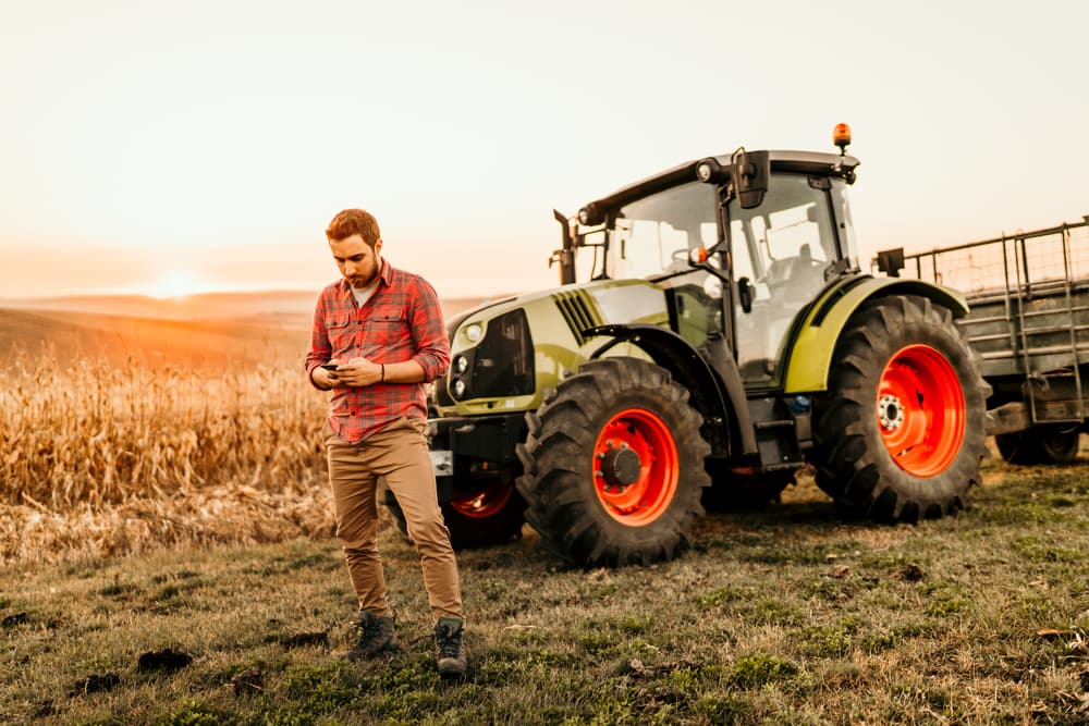 farmer with tractor on phone in field