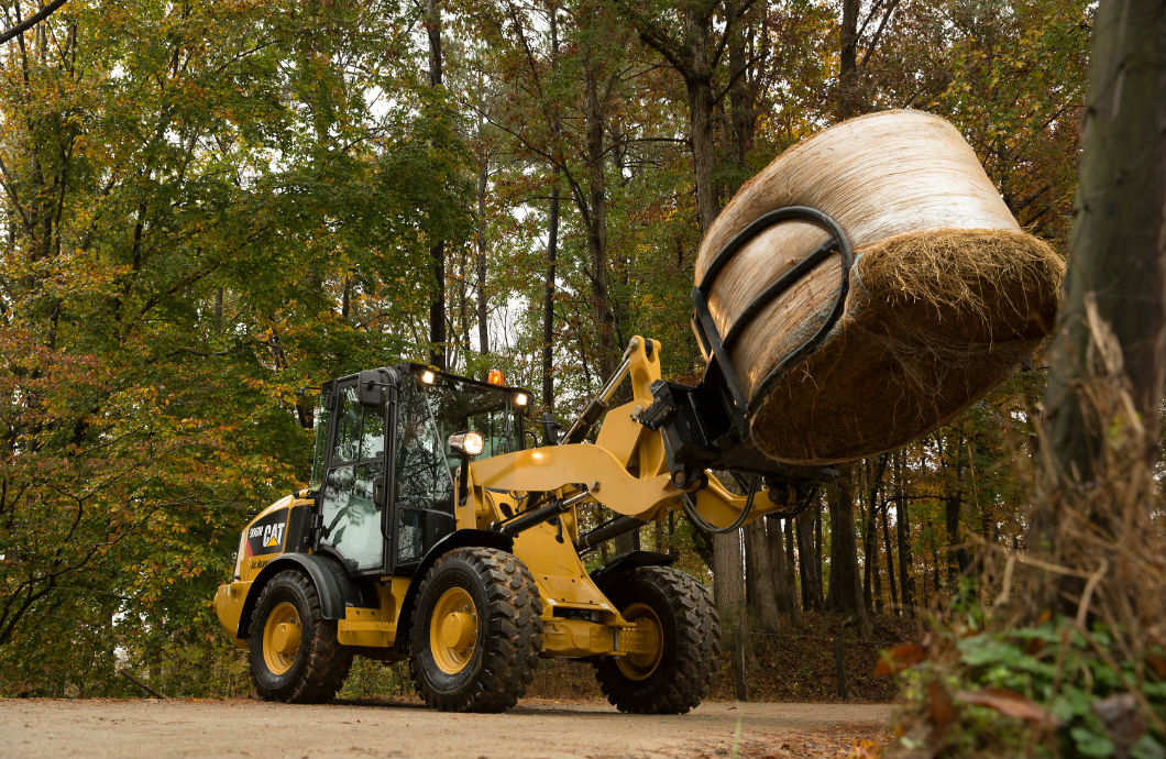 Cat M Series Ag Handler compact wheel loader with hay bale